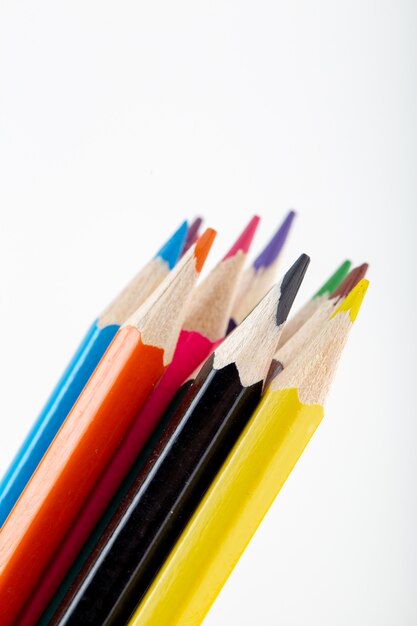 Crayons colorés alignés vue rapprochée pour le dessin et la peinture sur mur blanc