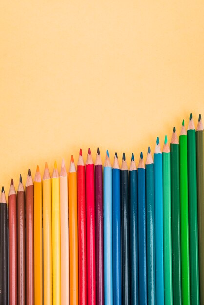 Crayons colorés sans soudure disposés en rangée sur une surface jaune