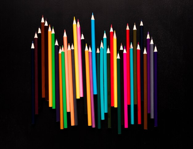 Crayons de couleurs vives placés sur fond noir