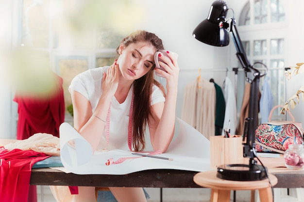 Créateur de mode travaillant en studio assis sur le bureau