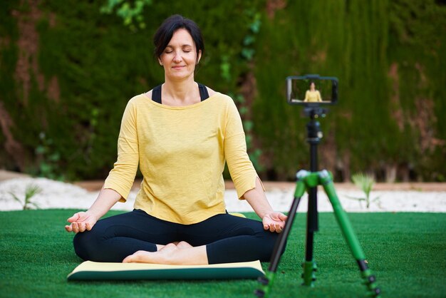 Une créatrice de contenu s'enregistre en train de faire du yoga pour sa chaîne de médias sociaux