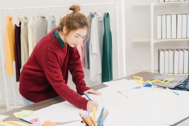 Créatrice de mode féminine asiatique belle professionnelle travaillant avec des croquis de tissu