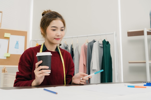 Créatrice de mode féminine asiatique belle professionnelle travaillant avec des croquis de tissu