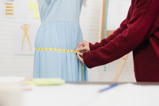 Créatrice de mode professionnelle belle asiatique travaillant la robe de mesure sur un vêtement mannequin