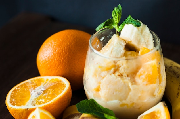 Crème glacée à la banane et aux oranges dans un verre avec garnitures à la menthe