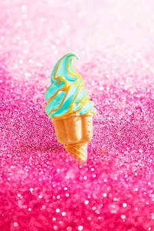 Crème glacée molle verte dans un cône sur une surface de paillettes roses