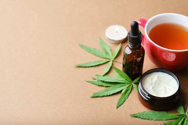 Crème d'huile cosmétique de cannabis dans une bouteille de pot à base de plantes et une feuille de plante verte Cosmétique naturel sur fond marron Espace de copie plat