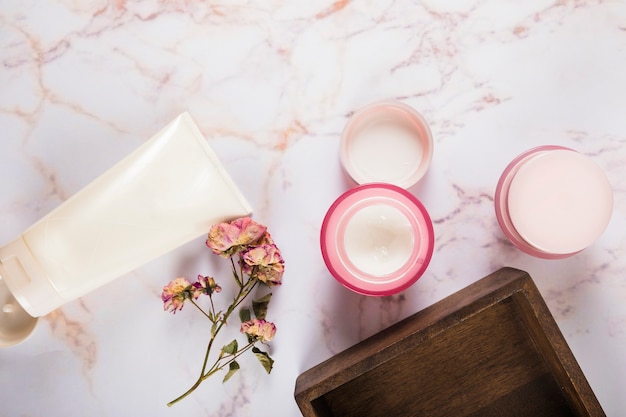 Crème hydratante avec des fleurs sur fond de marbre
