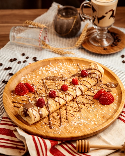 Crêpe roulée vue de face avec glaçage au chocolat et fraises