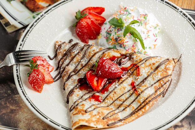 Crêpe sucrée avec de la poudre et des fraises