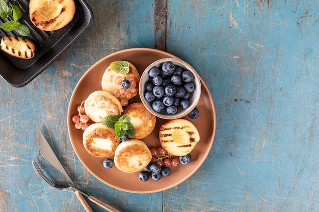 Photo gratuite des crêpes au fromage cottage avec des bleuets frais, des currants et des pêches sur une assiette un petit déjeuner sain et délicieux pour les vacances