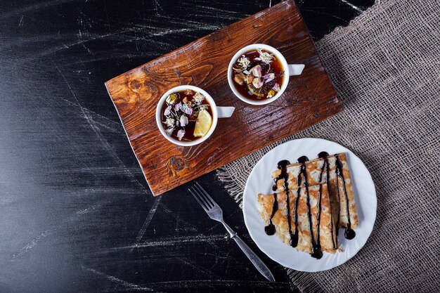 Crêpes dans une assiette blanche avec du sirop de chocolat et du thé.