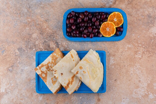 Crêpes à l'orange et aux cerises dans un plateau bleu