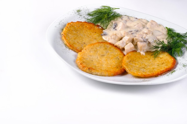 Crêpes de pommes de terre avec sauce à la viande sur une plaque blanche et fond blanc isolé