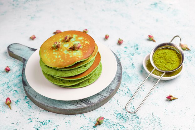 Crêpes vertes avec de la poudre de matcha avec de la confiture rouge sur une table lumineuse