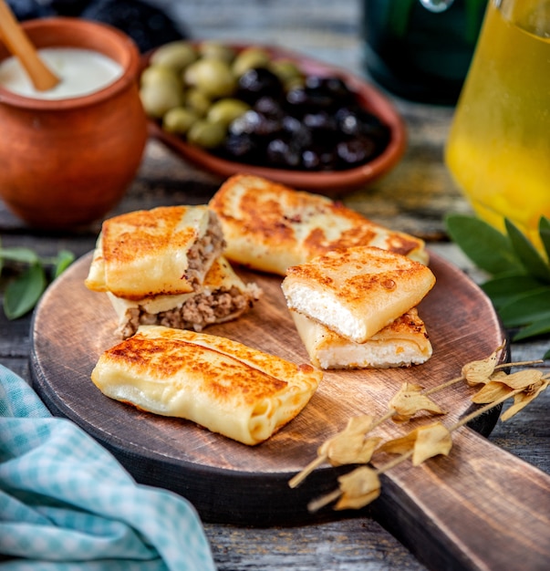 Crêpes à la viande et au fromage cottage sur une planche de bois