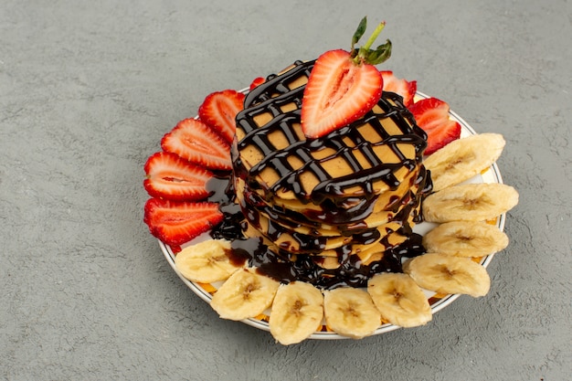 crêpes vue de dessus avec du chocolat et des fruits frais sur le sol gris