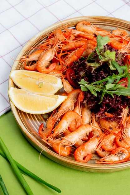 Crevettes bouillies servies avec des tranches de citron et des herbes