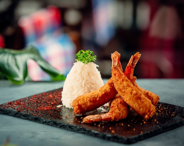 crevettes frites croustillantes avec du riz sur une planche en pierre noire