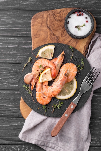 Photo gratuite crevettes de fruits de mer sur planche de bois et couverts