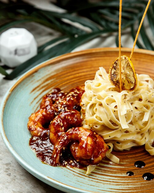 Crevettes en sauce teriyaki servies avec fettuccini