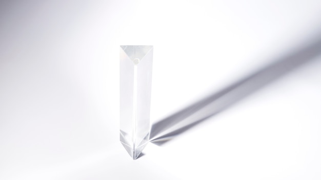Cristal de prisme triangulaire avec une ombre sombre sur fond blanc