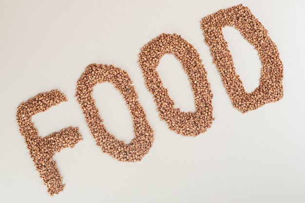 Écriture alimentaire avec des lentilles vertes sur fond blanc.