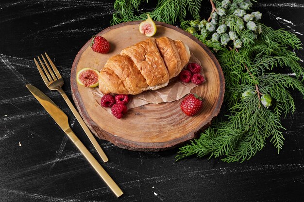 Croissant aux fruits rouges sur un plateau en bois.