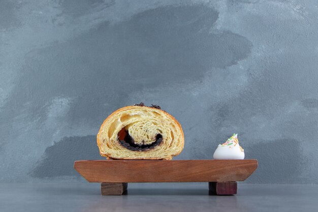 Croissant demi-coupé au chocolat sur planche de bois.