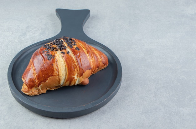 Croissant frais décoré de goutte de chocolat sur tableau noir.