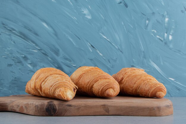 Croissant savoureux à bord, sur le fond de marbre. Photo de haute qualité