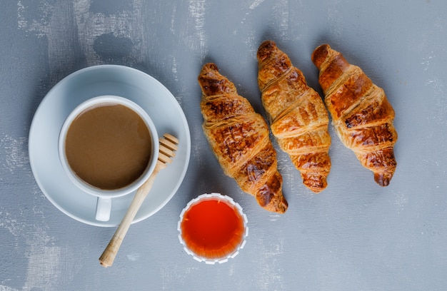 Photo gratuite croissant avec tasse de café, miel, louche, vue de dessus.