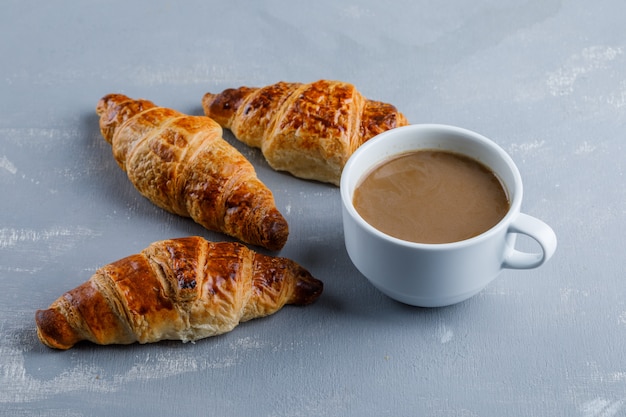 Croissant avec tasse de café, vue grand angle.