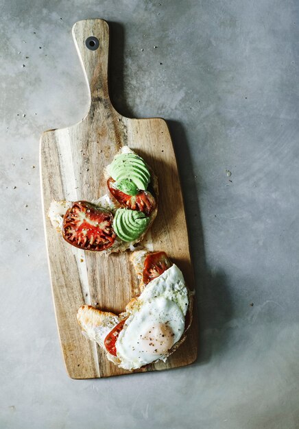 Croissant avec tomates anciennes, avocat et oeuf au plat