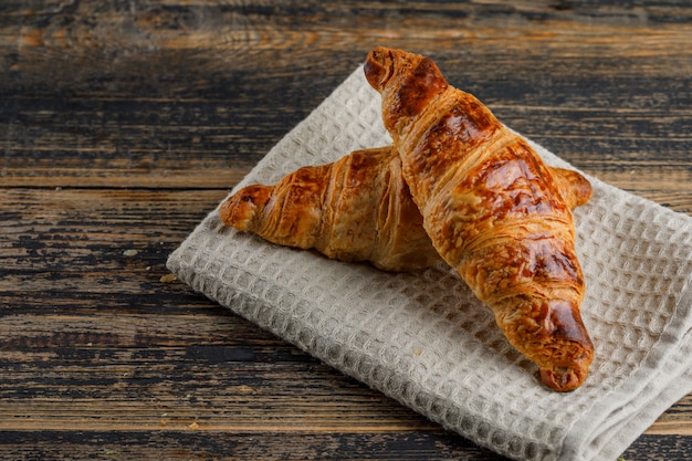 Croissant sur torchon en bois et cuisine, vue grand angle.