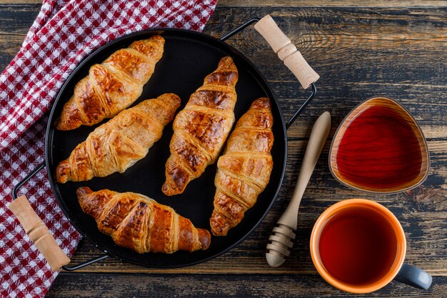 Croissants dans une casserole avec une tasse de thé, de miel, plat de louche poser sur une serviette en bois et de cuisine