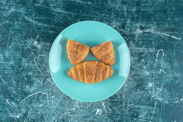 Photo gratuit croissants faits maison sur une assiette, sur fond bleu. photo de haute qualité