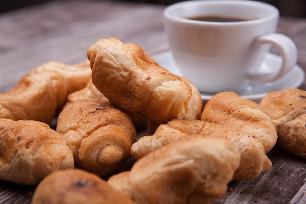 Croissants fraîchement préparés sur une table en bois rustique avec une tasse de café. Café délicieux.