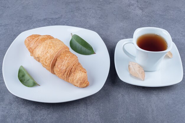 Croissants français frais avec une croûte dorée avec une tasse de thé.