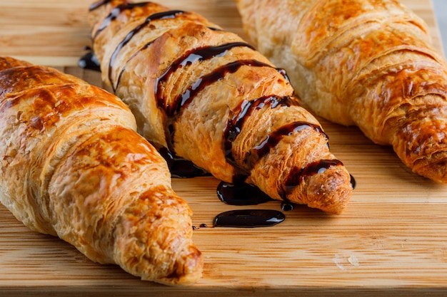 Croissants à la sauce au chocolat gros plan sur une table en bois