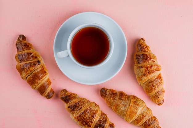 Croissants avec tasse de thé plat posé sur une table rose