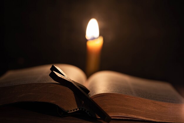 Croix avec bible et bougie sur une vieille table en bois de chêne.