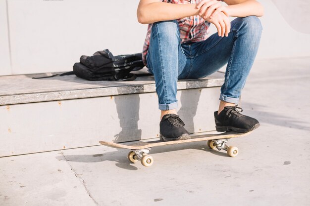 Photo gratuite crop adolescent gardant les pieds sur la planche à roulettes