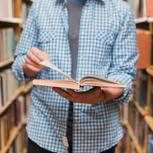 Crop adolescent livre de lecture entre les bibliothèques