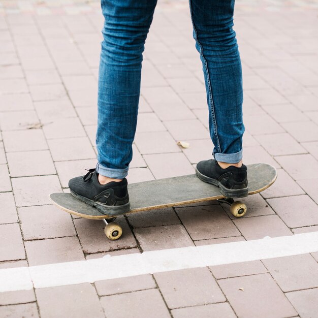 Crop adolescent sur skateboard près de piste cyclable
