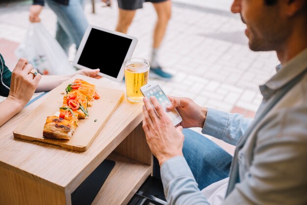 Crop couple avec des gadgets dans le café de la rue