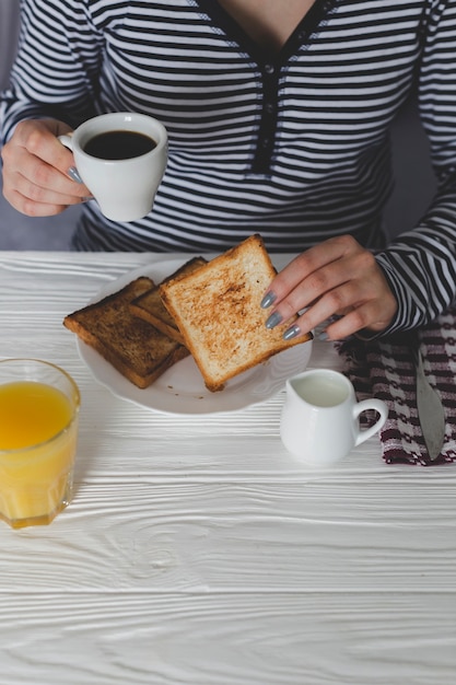 Crop femme petit déjeuner avec du café et des toasts