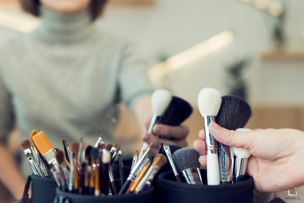 Crop femme prenant des pinceaux de maquillage