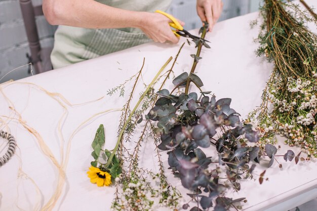 Crop femme préparant des fleurs pour le bouquet