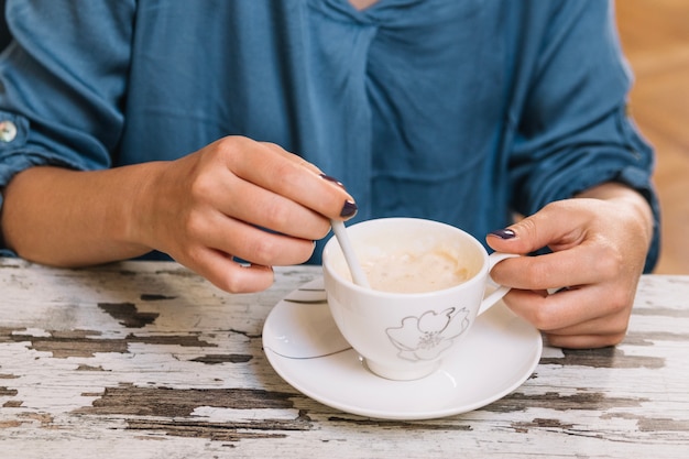 Crop femme en remuant le café